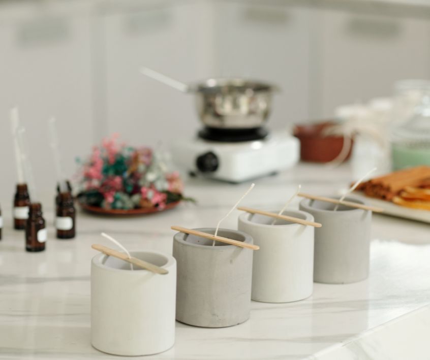 Supplies for candle making on a kitchen countertop. Scents, heat plate with wax melter and candle forms.