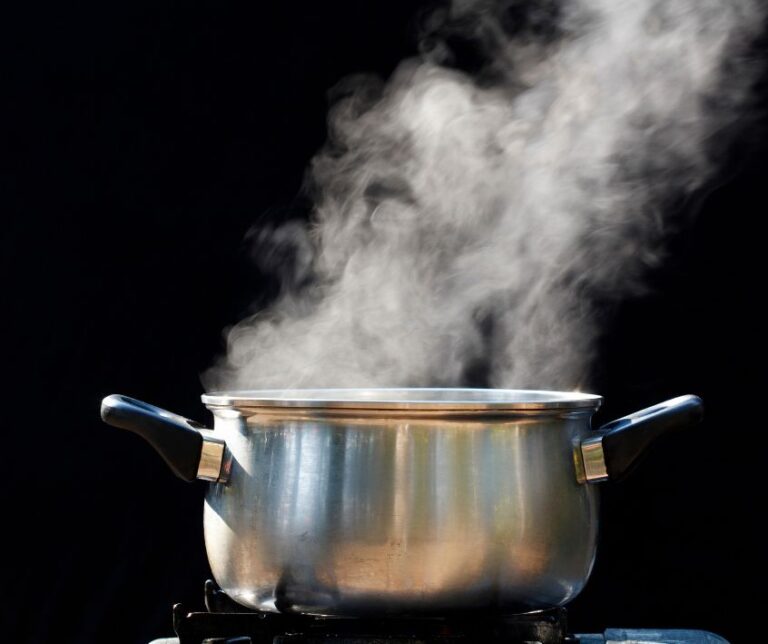 A two handled pot steaming on a kitchen stove.