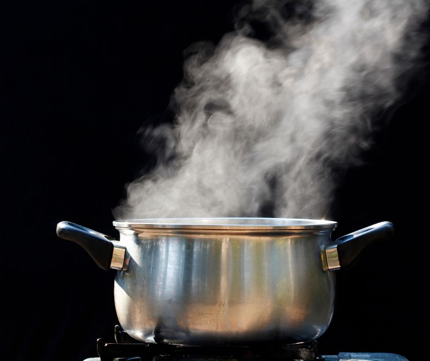 A two handled pot steaming on a kitchen stove.
