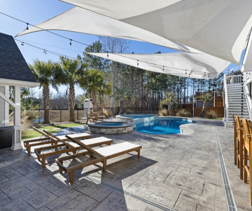 Outdoor pool patio with beach chairs and shade sails.