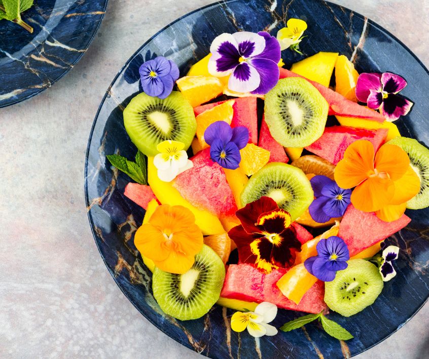 Vibrant Fruit Salad with Mango, Watermelon, Kiwi and Colorful Edible Flowers.