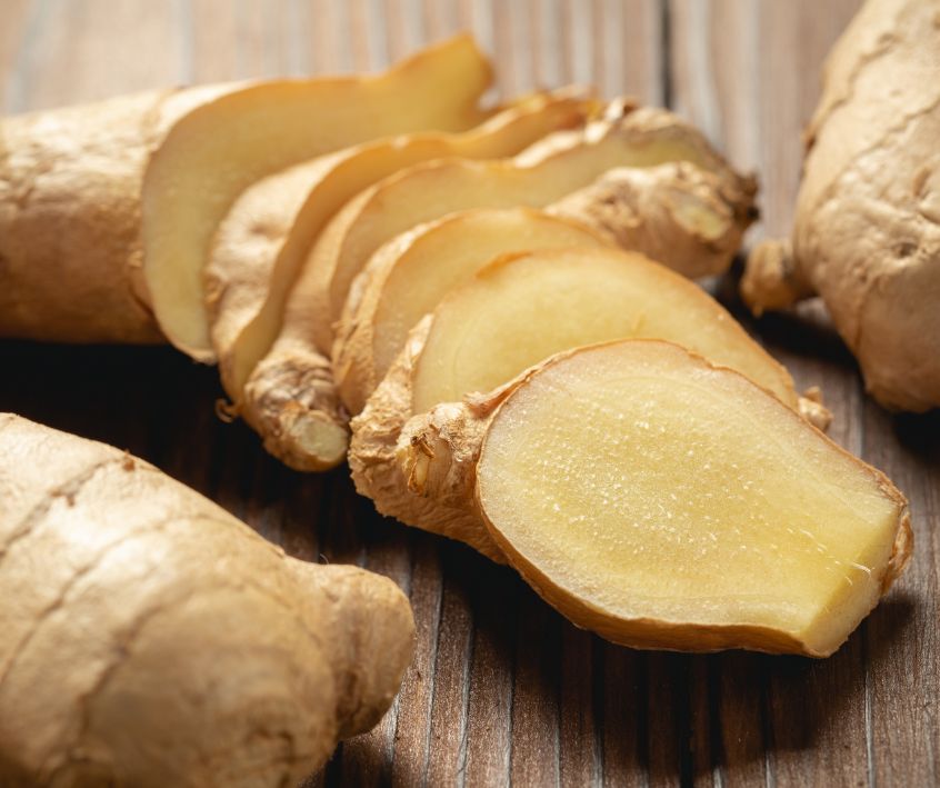 Sliced fresh ginger root on a wooden table.
