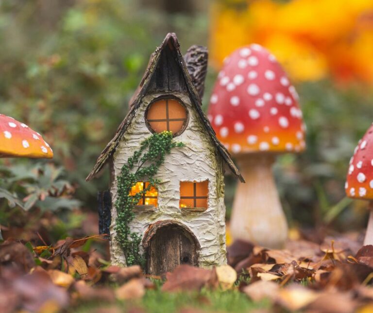 Small fairy house next to toadstool garden art.