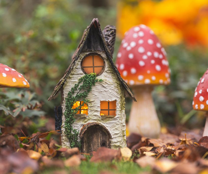 Small fairy house next to toadstool garden art.