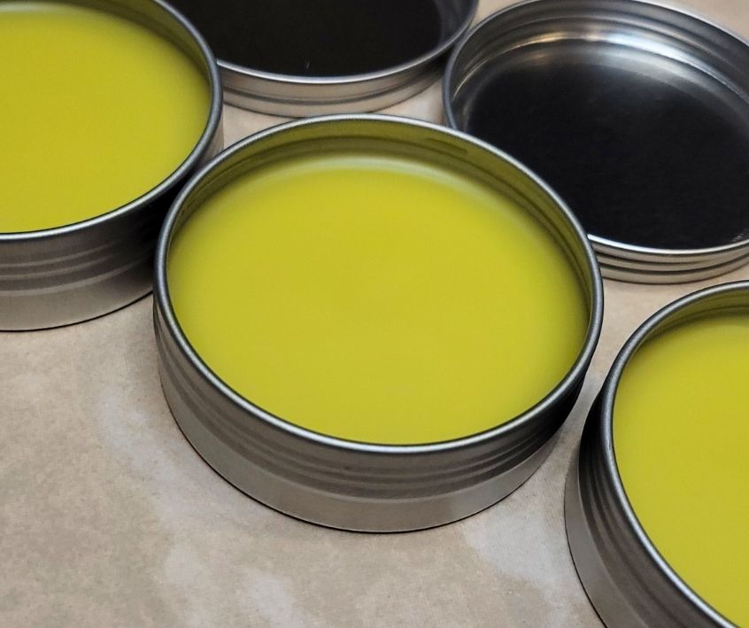 Solid yellow homemade wood polish in three tins with screw on lids.