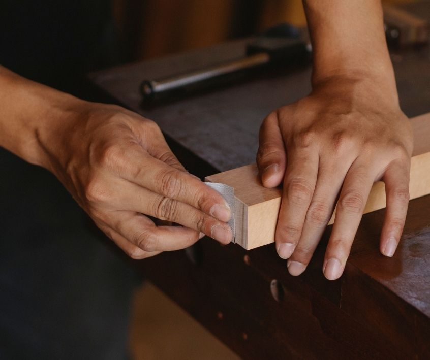 Person finishing a wooden frame with sandpaper.