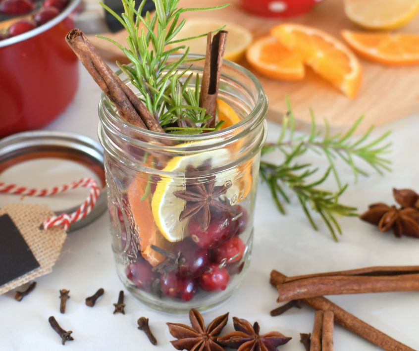 Cranberries, cinnamon sticks, cloves, dried citrus and pine sprigs packed into jelly mason jars as gifts.
