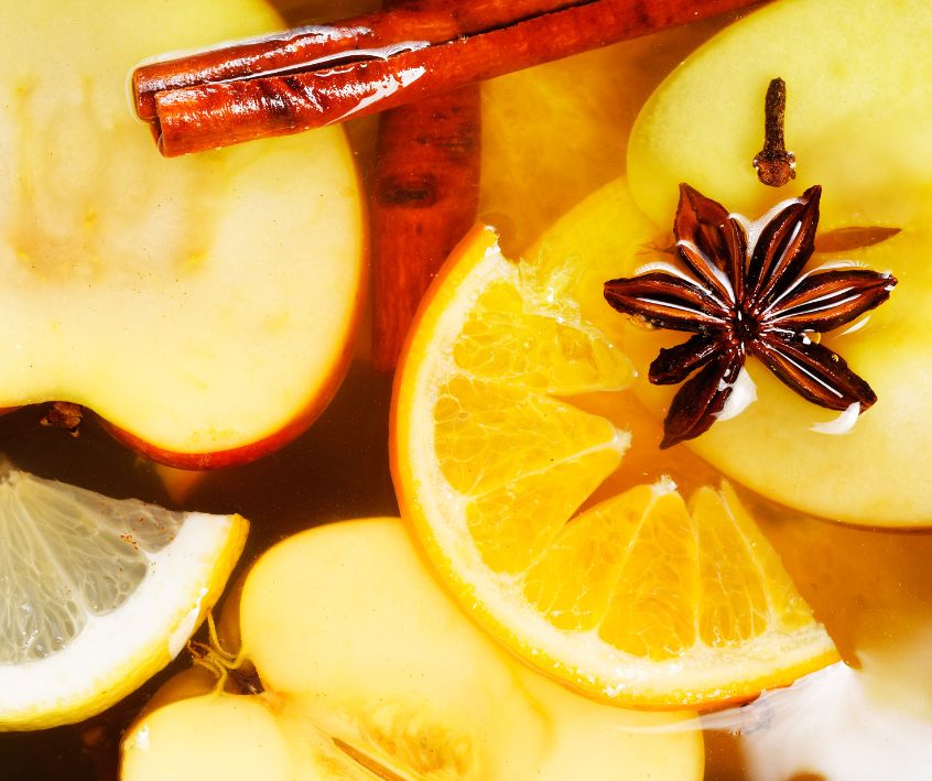 A simmer pot made with sliced oranges, lemons, apples, cinnamon sticks, star anise, and whole cloves.