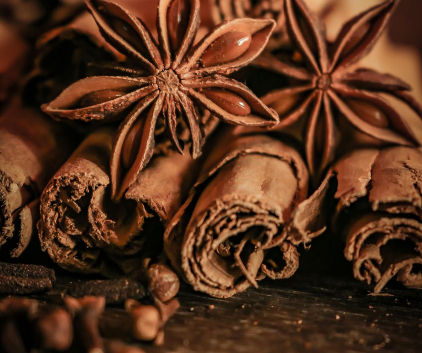 Star Anise, Cinnamon Sticks, Whole Cloves on a wooden table top.