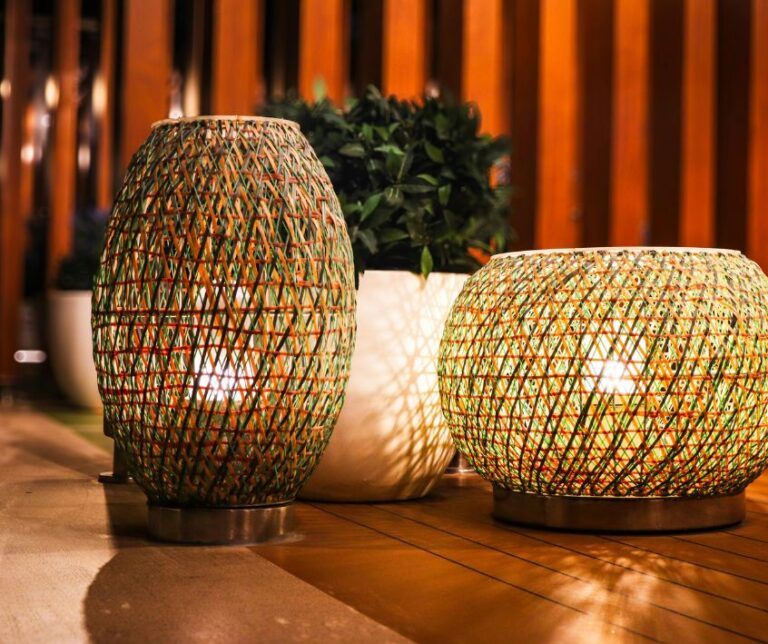 Woven fiber patio lanterns on a wood deck next to potted plants.