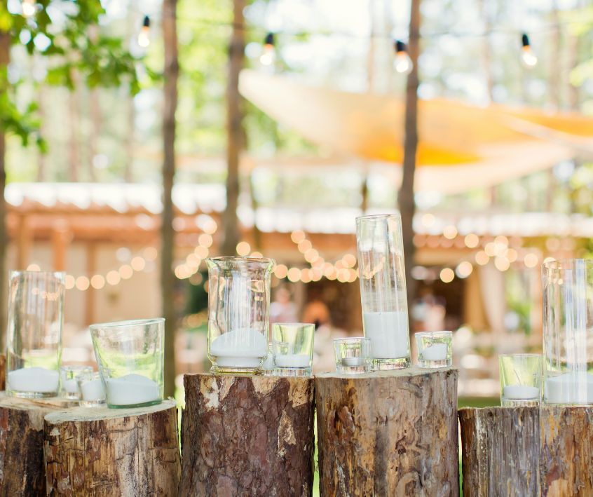 Outdoor decorations of string lights and candles on stumps.
